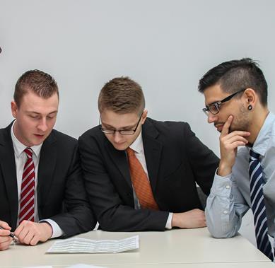 Executives and a consultant review documents at a table.